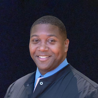 Dentist Charley Cheney III Smiling In Front Of Dark Blue Background