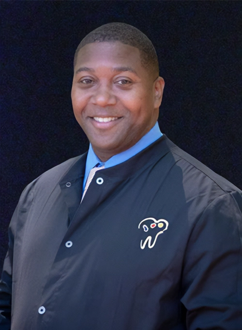 Dentist Charley Cheney III Smiling In Windbreaker With Clinic Logo